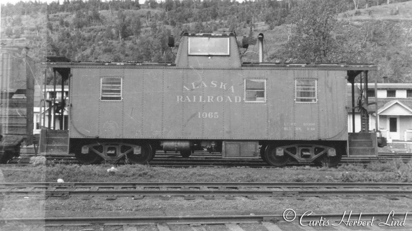 Caboose 1065 was built 3-1949 by PC&F. The location is Healy yard.  The buildings behind the caboose are two Railroad owned duplexes. 