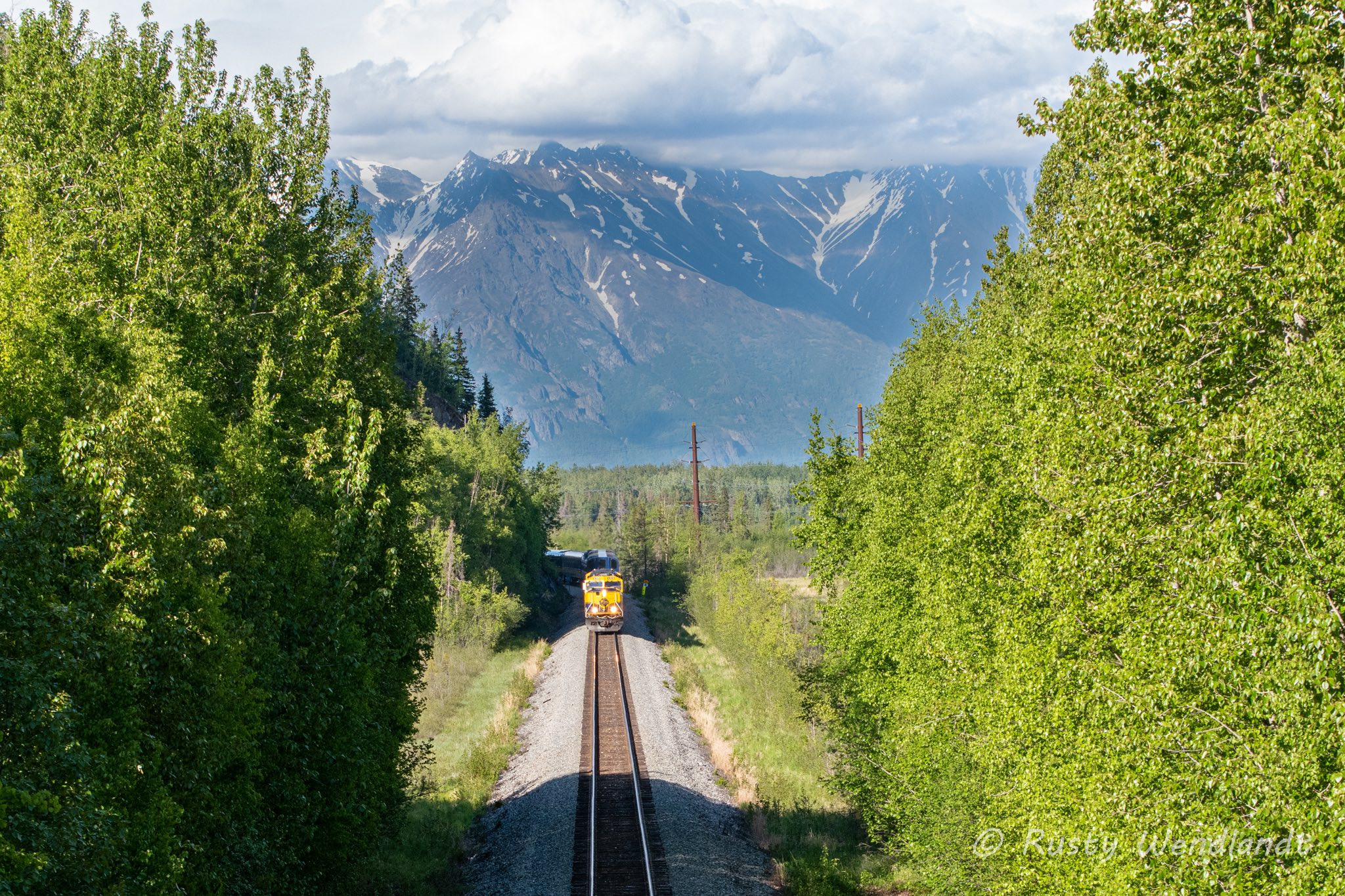 The Denali Star is on the way back to Anchorage dwarfed by the mountains as it is making its way under the Old Glenn Highway.